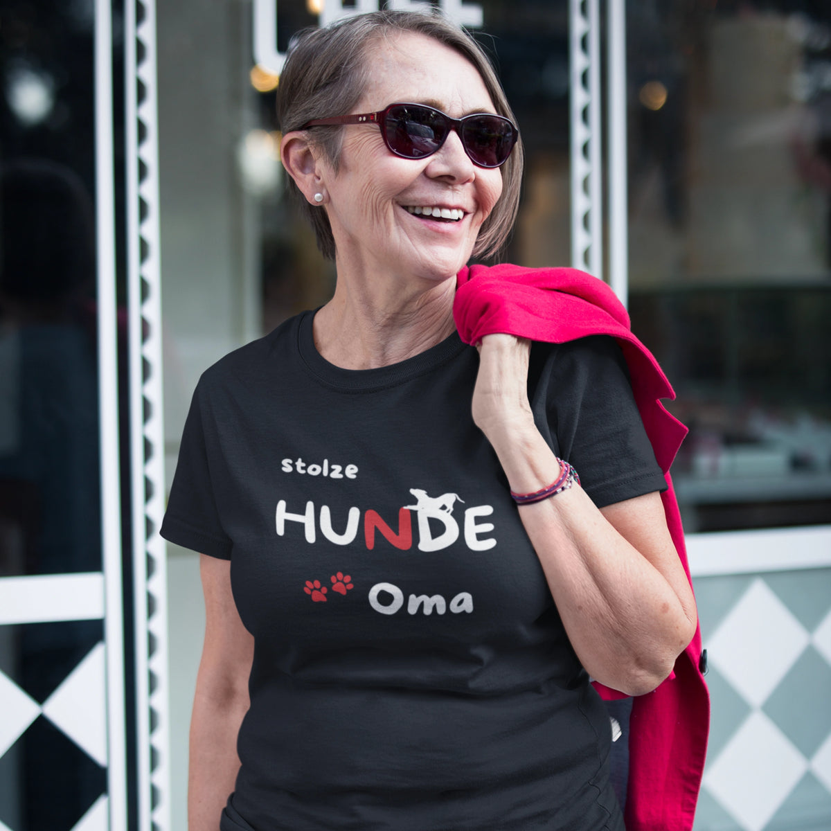 Frau trägt ein schwarzes Damen T-Shirt mit dem Aufdruck „stolze HUNDE Oma“, Hundesilhouette und Pfoten.